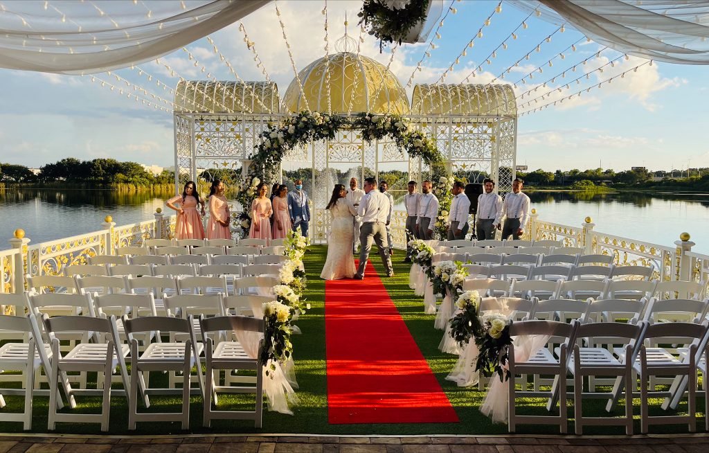 Outdoor ceremony aisle with red carpet and floral arch